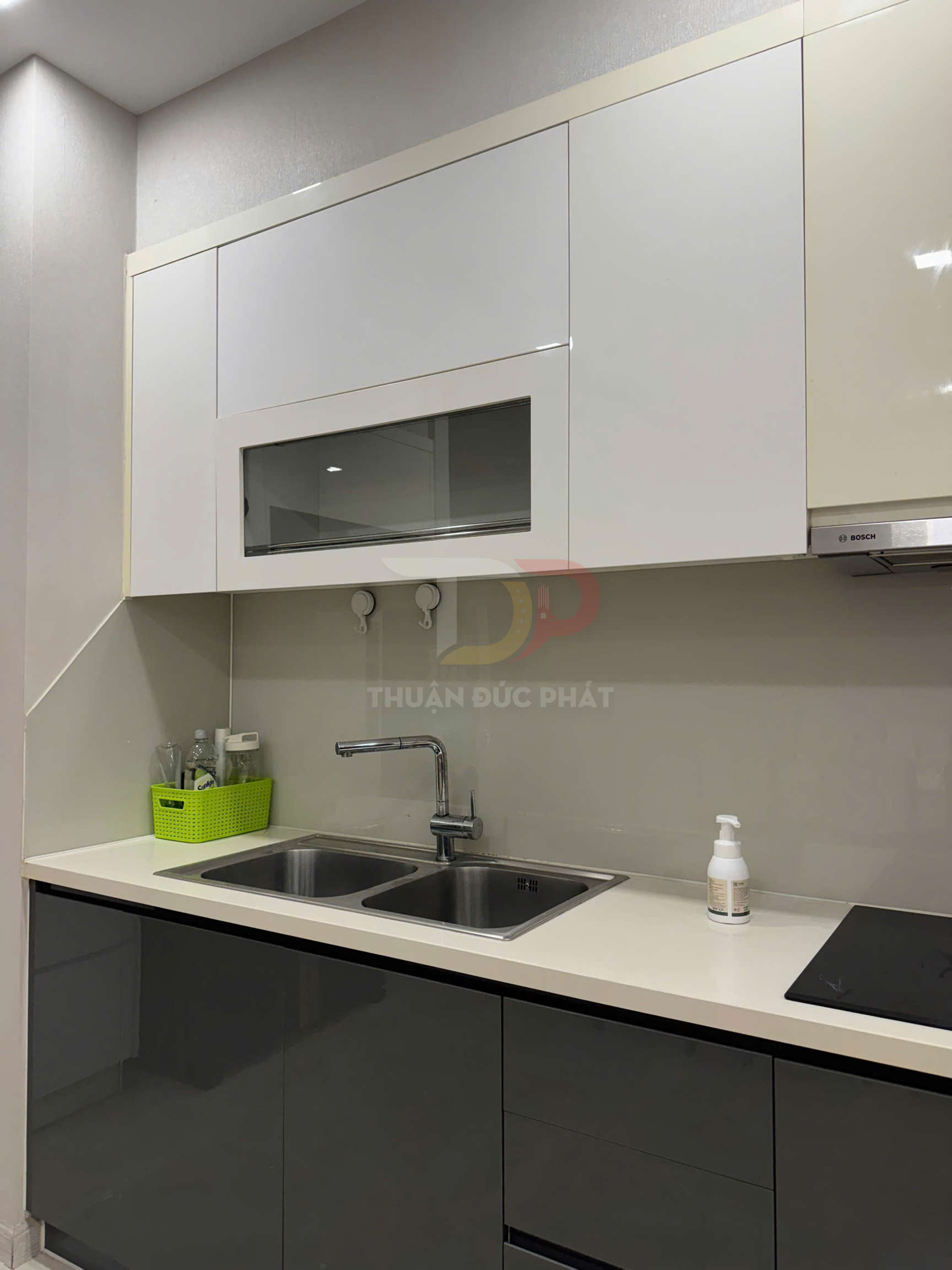 Tủ bếp hiện đại với chậu rửa đôi inox, vòi nước, bếp từ Bosch và kệ trên màu trắng sáng