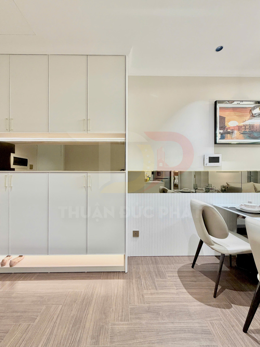 Tủ giày âm tường màu trắng hiện đại cạnh bàn ăn và ghế bọc da trong căn hộ nhỏ gọn
