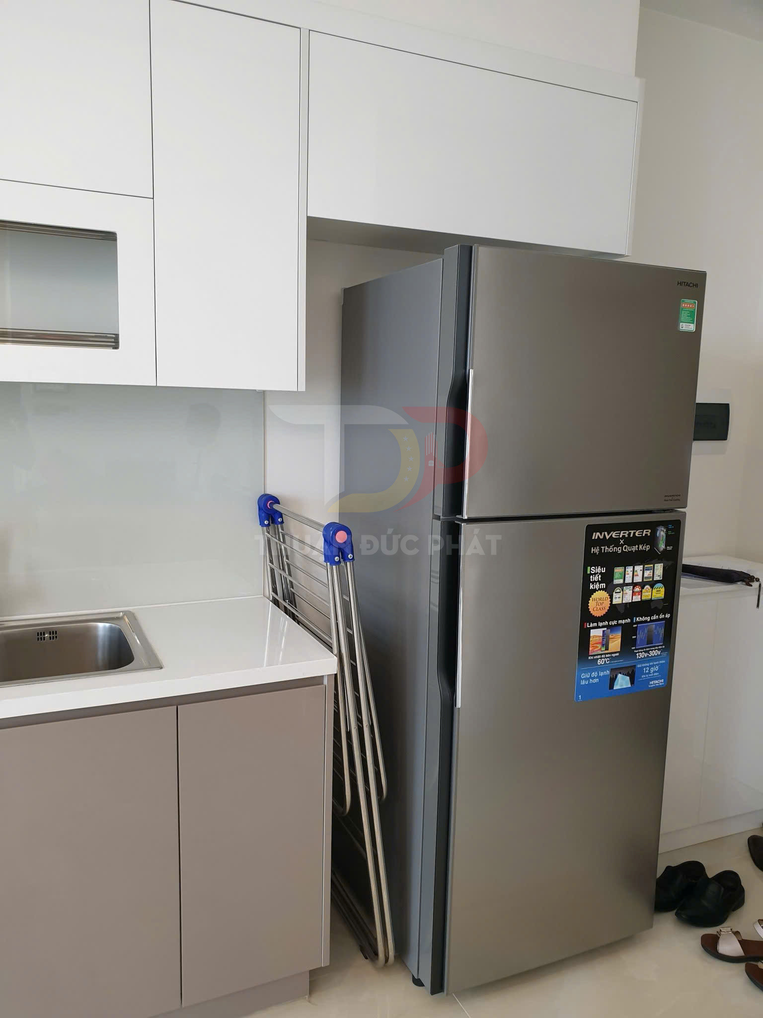 Tủ lạnh Hitachi Inverter màu bạc đặt trong bếp hiện đại cạnh bồn rửa và kệ phơi đồ gấp gọn