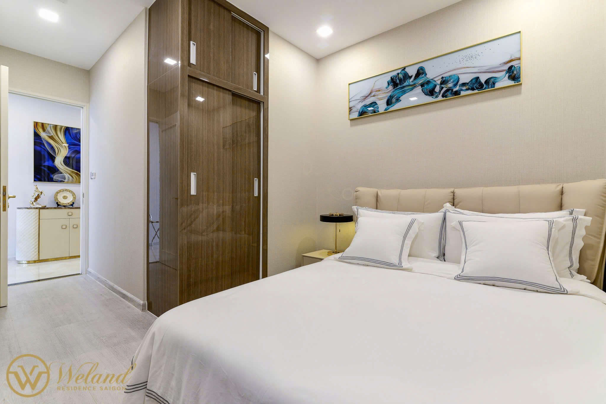 Phòng ngủ chung cư hiện đại với giường nệm trắng, tủ quần áo gỗ và tranh treo tường trang trí cao cấp