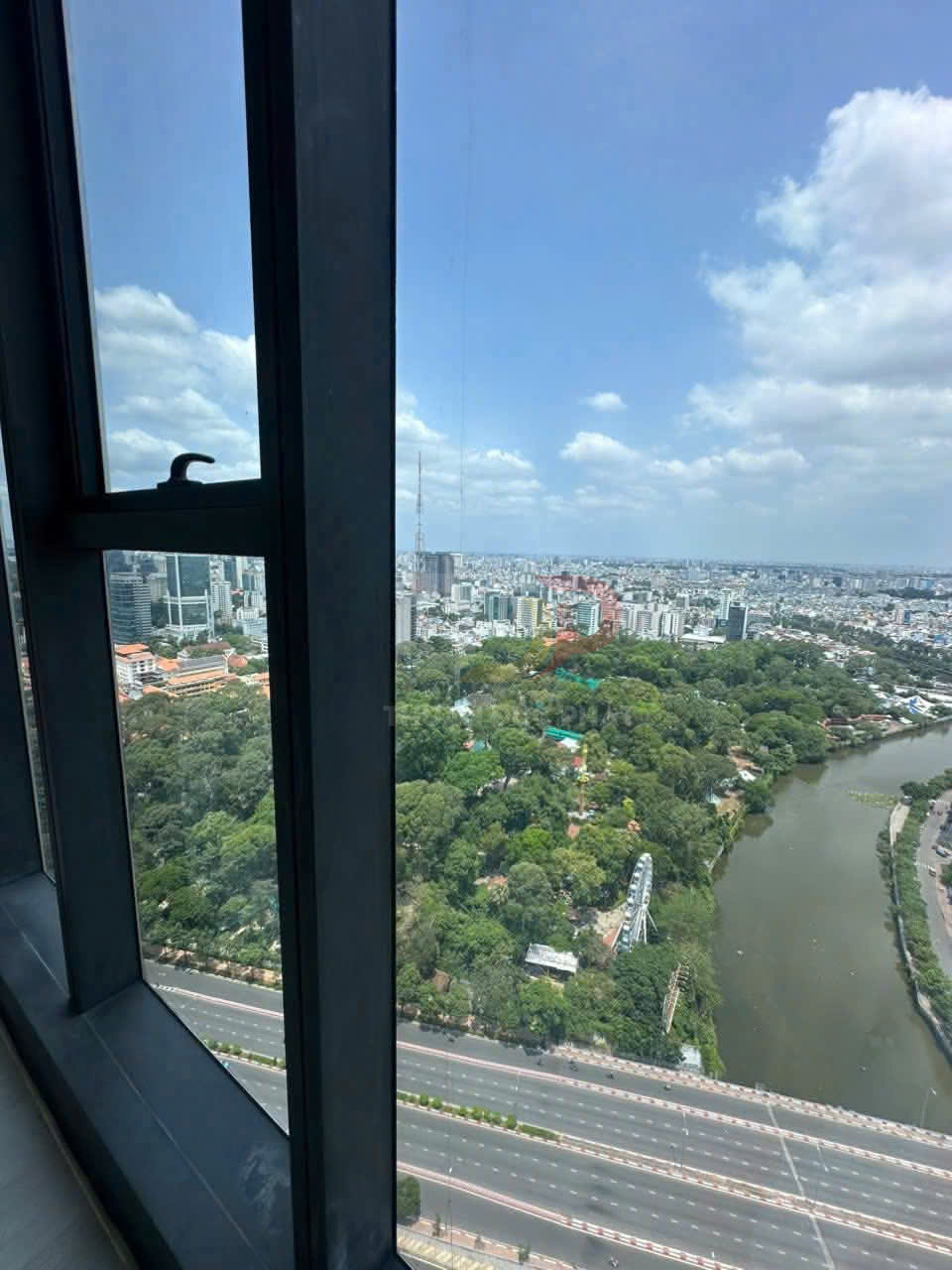 Cửa sổ kính lớn nhìn ra công viên cây xanh, sông và đường cao tốc trong khu đô thị đông đúc