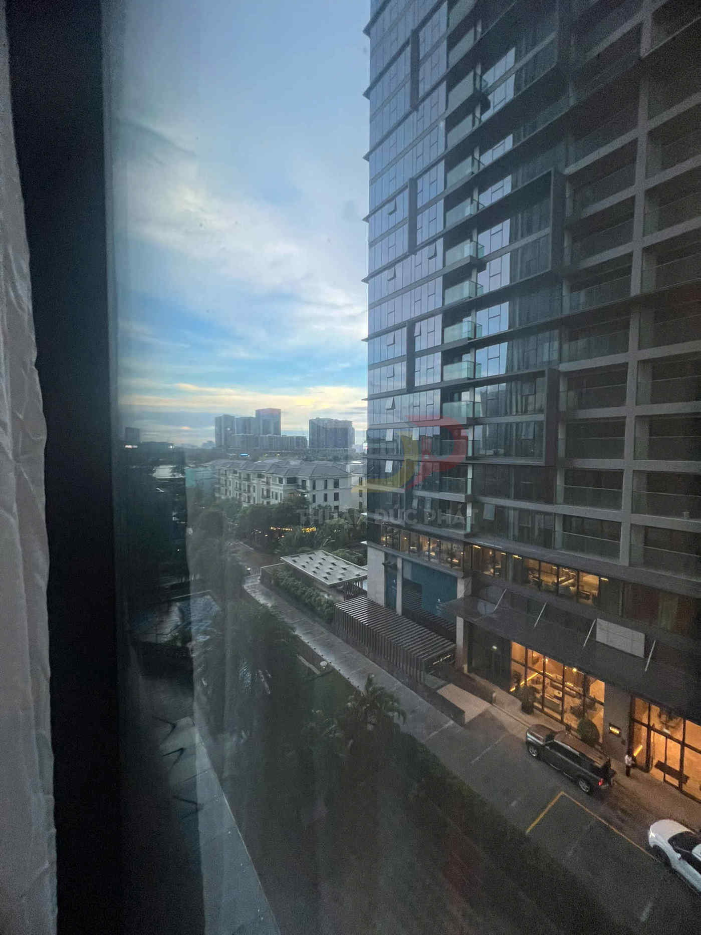 Cảnh nhìn từ cửa sổ khách sạn xuống tòa nhà chung cư cao tầng và đường phố lúc hoàng hôn